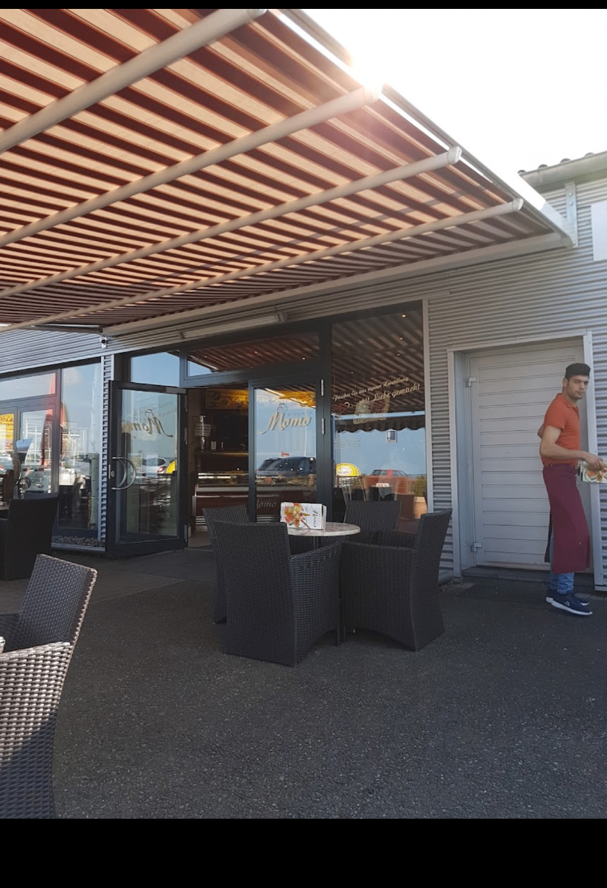 Sonnige Terrasse von Eiscafé Momo mit roten Sonnenschirmen